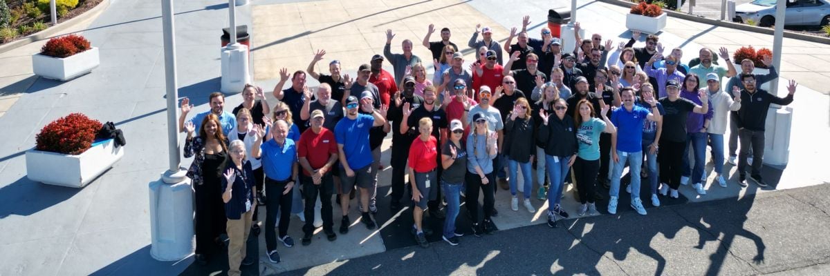 Teammates from several Speedway Motorsports subsidiaries, including Charlotte Motor Speedway, PRN, US Legend Cars International and SMIP pose for a photo in front of CMS